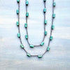 Two turquoise beaded necklaces on a light wooden surface