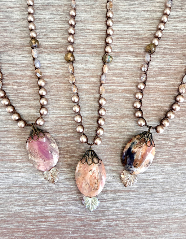 Three pearl necklaces with stone pendants on a wooden surface