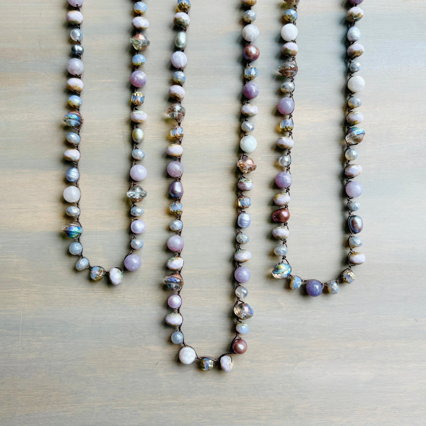 Three pearl necklaces on a wooden surface