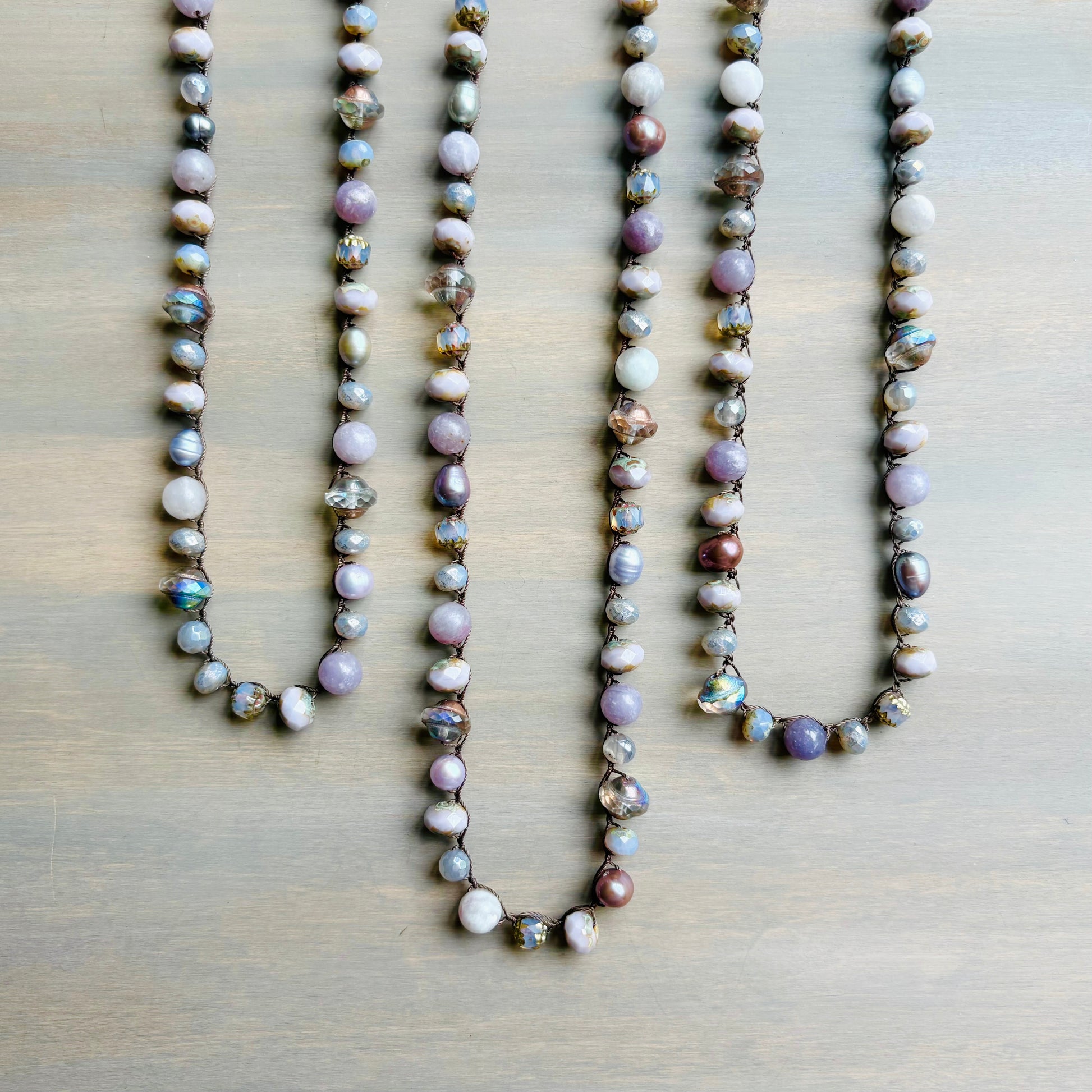 Three pearl necklaces on a wooden surface