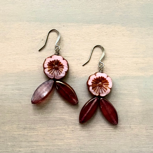 Pair of earrings with floral design on a wooden surface