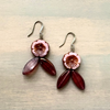 Pair of earrings with floral design on a wooden surface