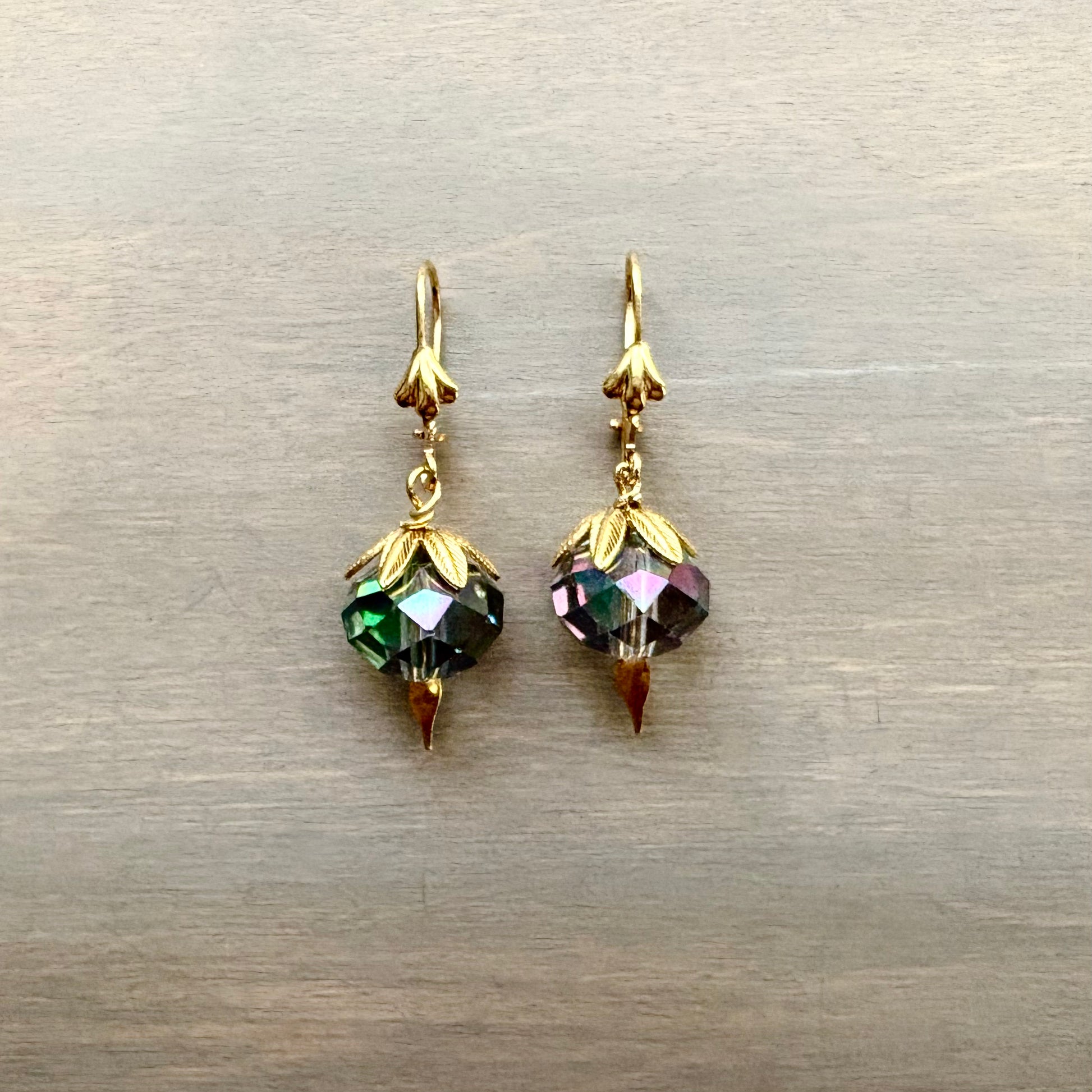 Gold earrings with colorful beads on a metallic surface