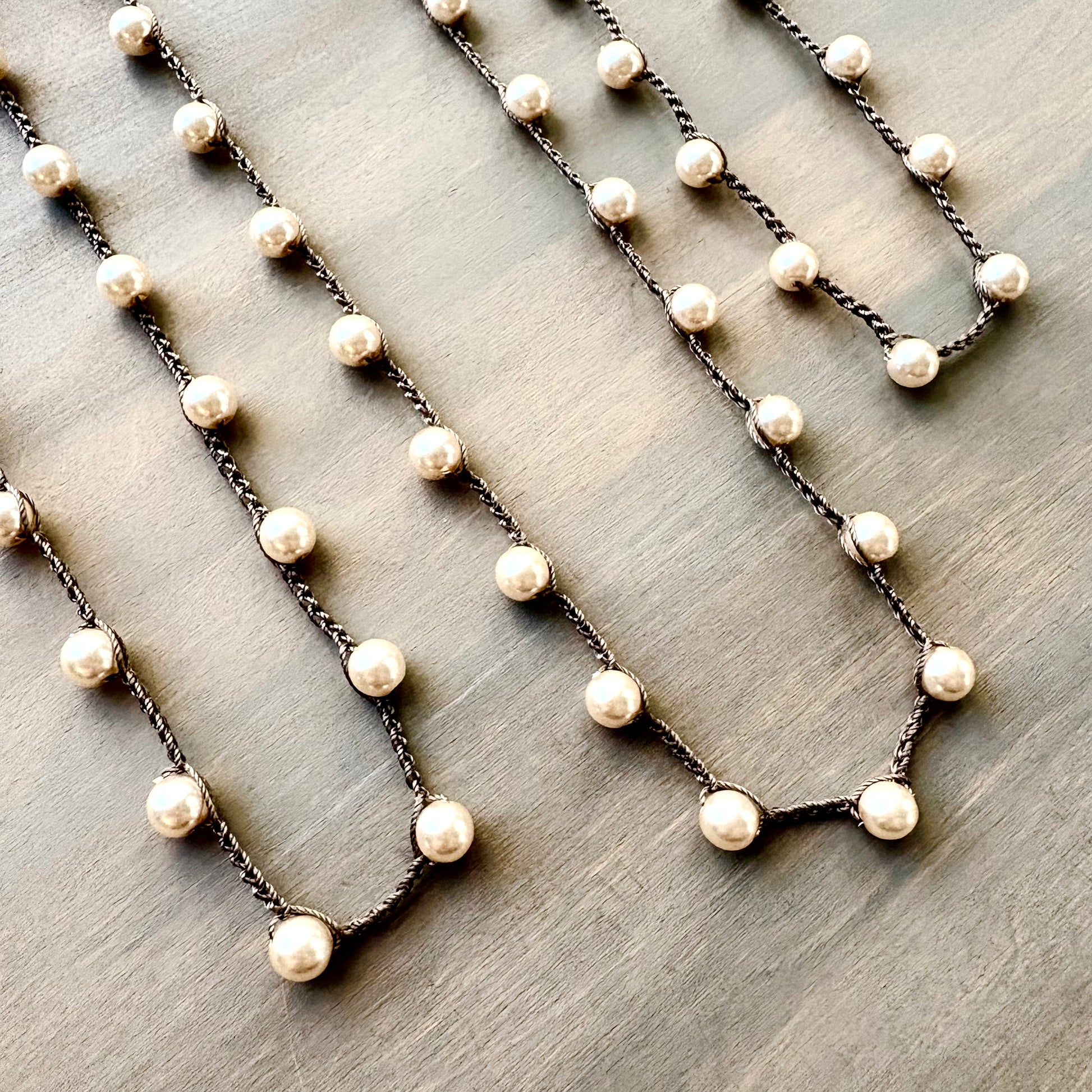 Necklaces with pearl-like beads on a wooden surface
