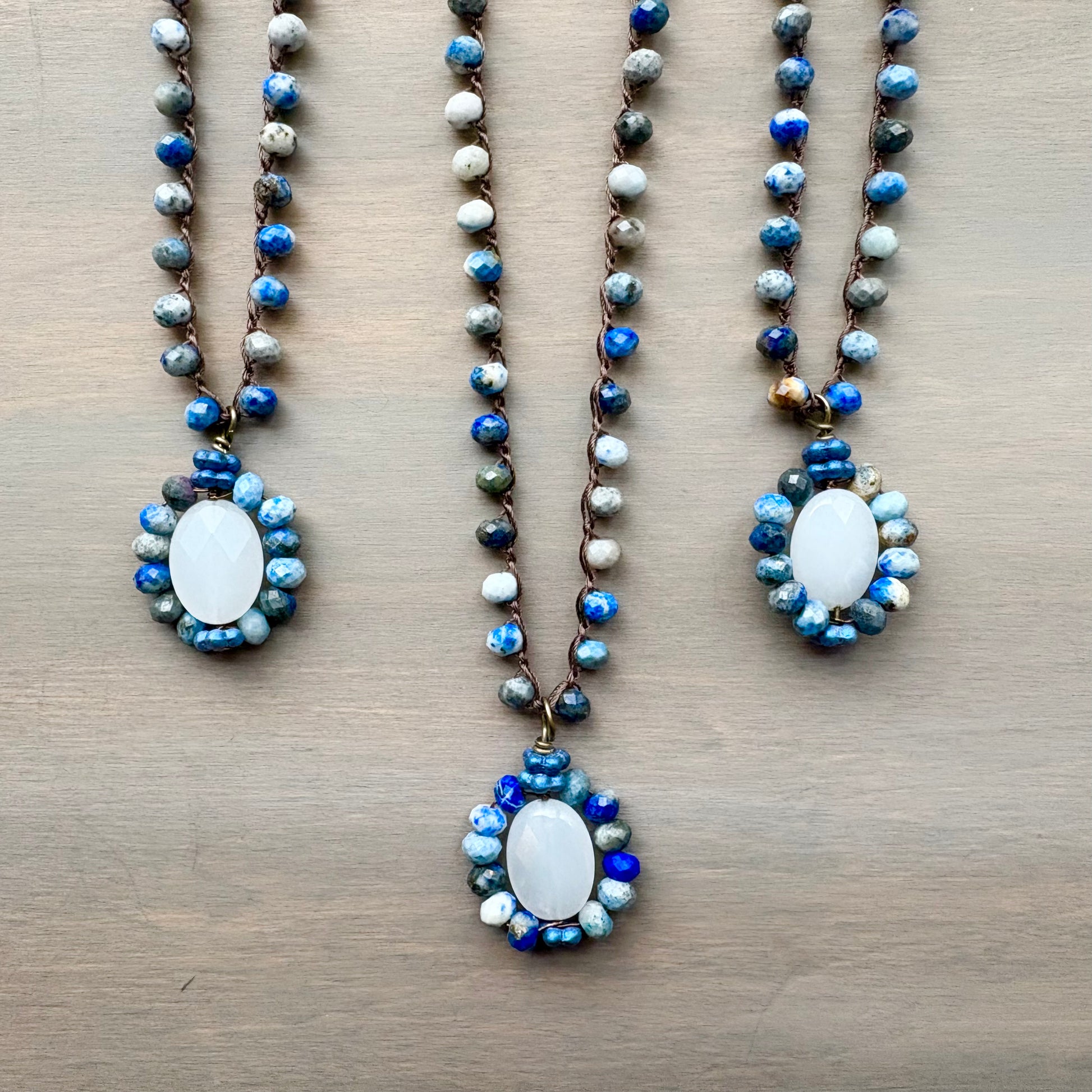 Three beaded necklaces with white stone pendants on a wooden surface