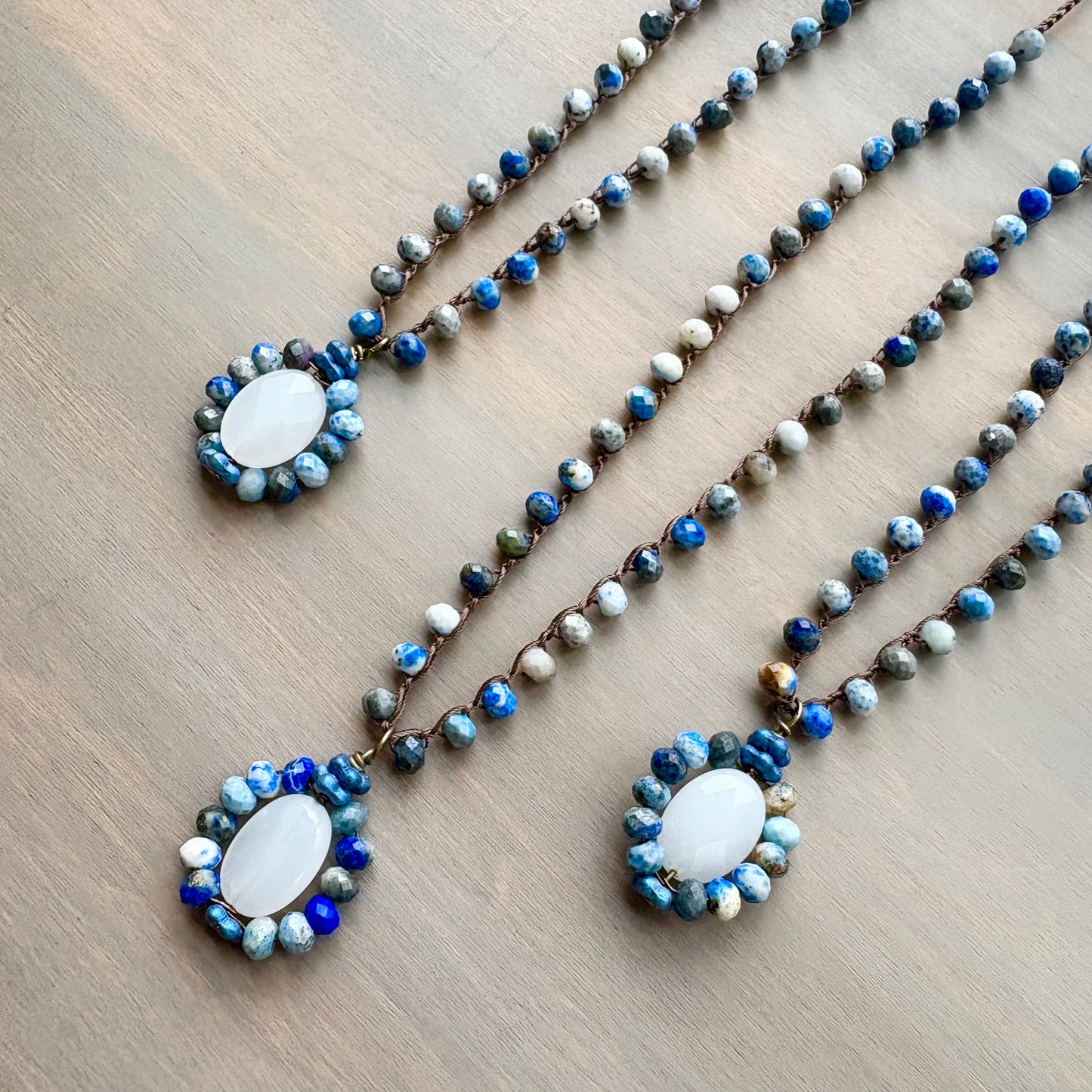 Three beaded necklaces with a central pendant on a wooden surface