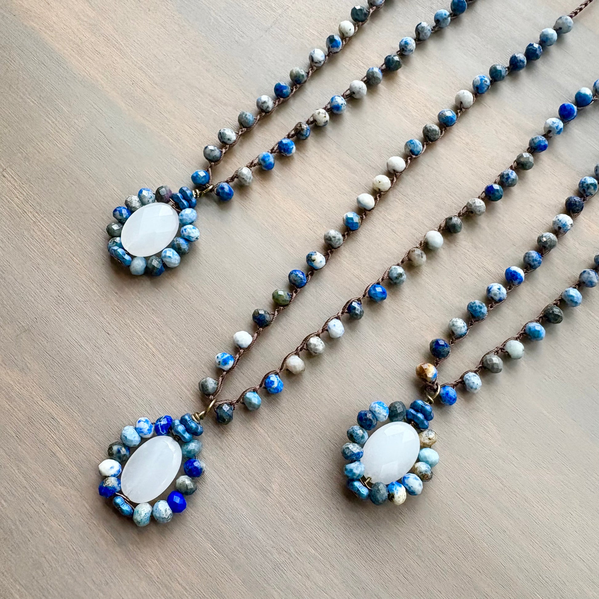 Three beaded necklaces with a central pendant on a wooden surface