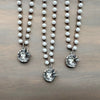 Three pearl necklaces with silver bird nest pendants on a wooden surface