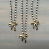 Three pearl necklaces with gold bow pendants on a wooden surface