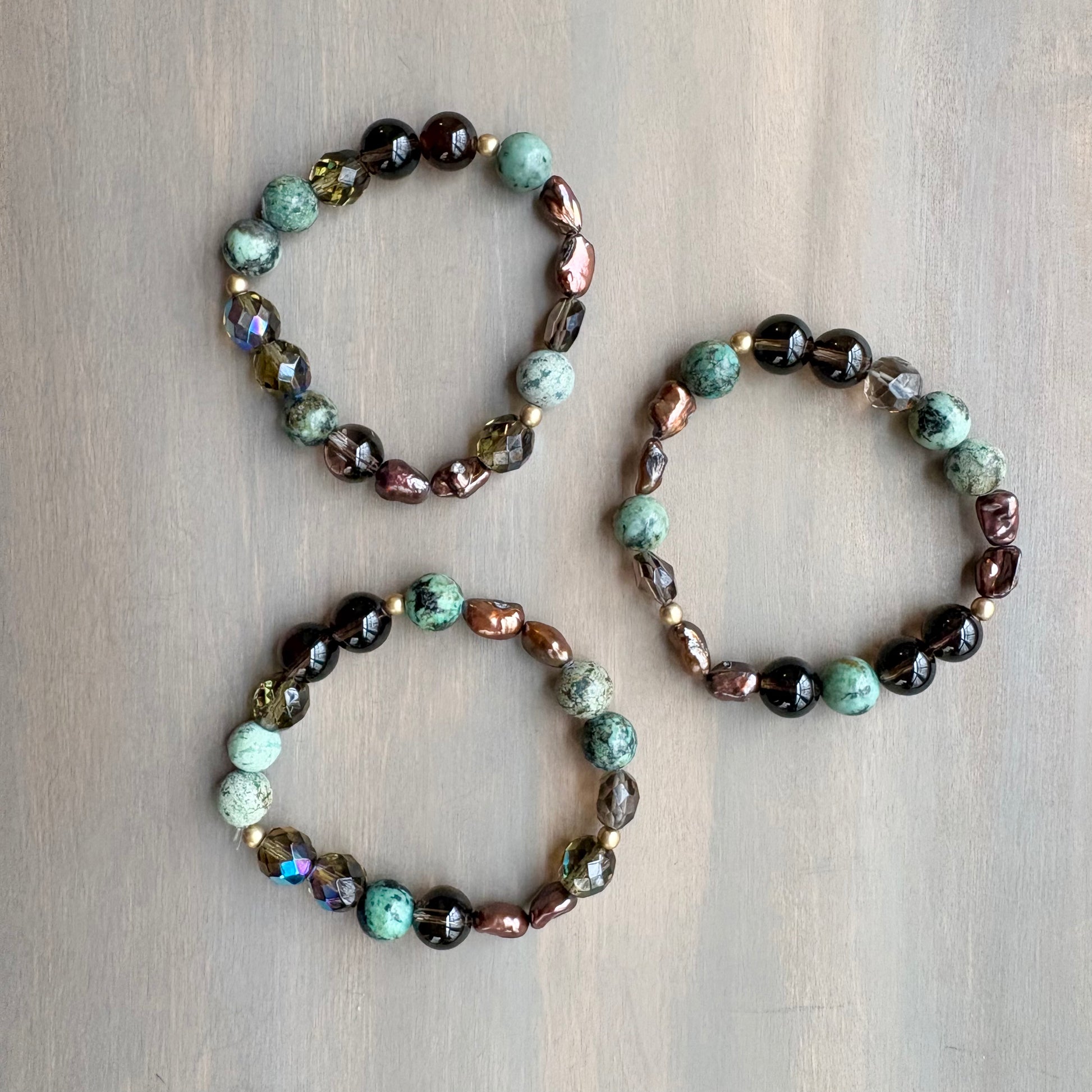 Three beaded bracelets on a wooden surface