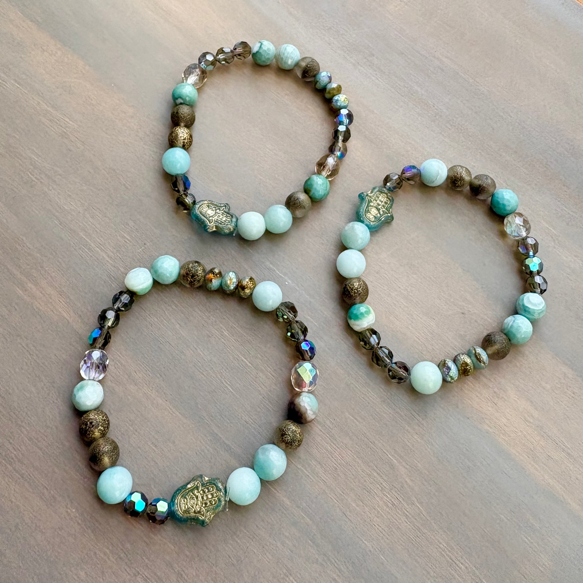 Three beaded bracelets with turquoise and brown beads on a wooden surface