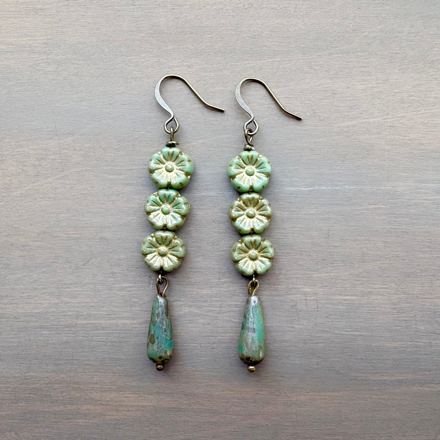 Pair of green floral earrings on a metallic surface