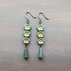 Pair of green floral earrings on a metallic surface