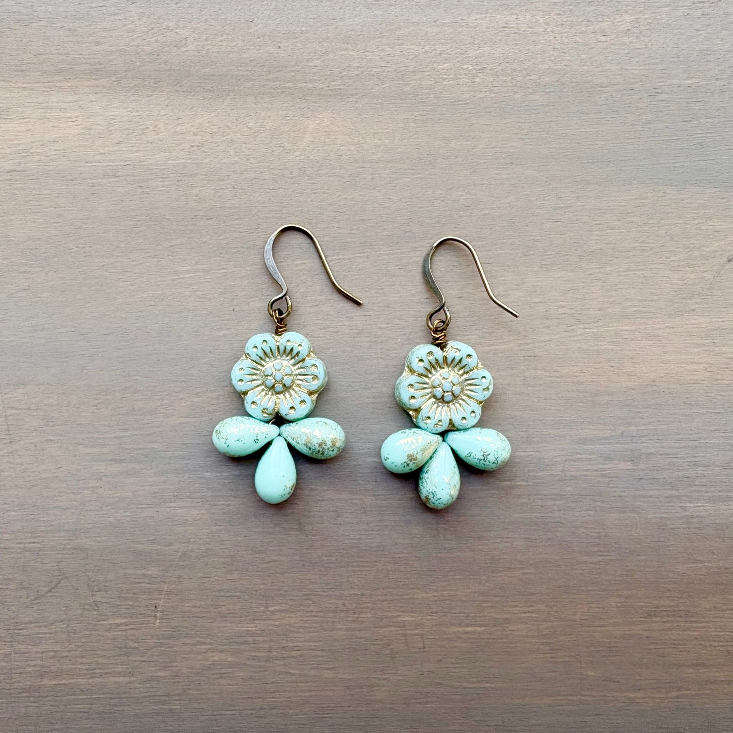 Pair of turquoise flower-shaped earrings on a wooden surface