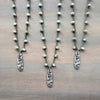 Three pearl necklaces with silver pendants on a wooden surface