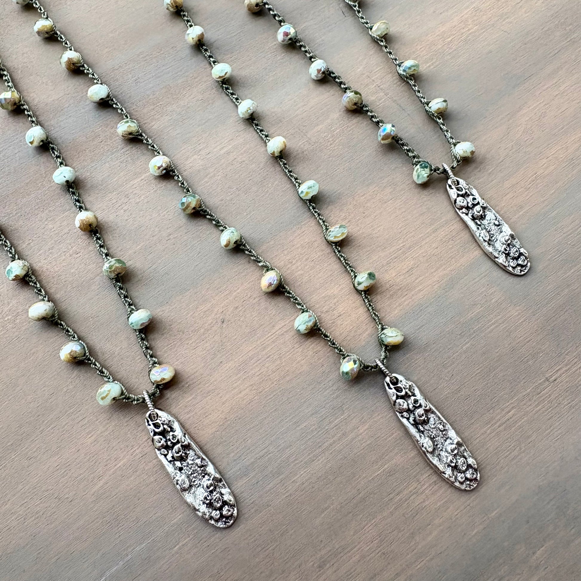 Necklace with pearl beads and silver pendants on a wooden surface