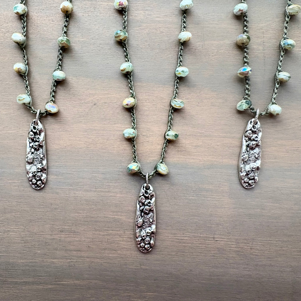 Three necklaces with pendant charms on a wooden surface