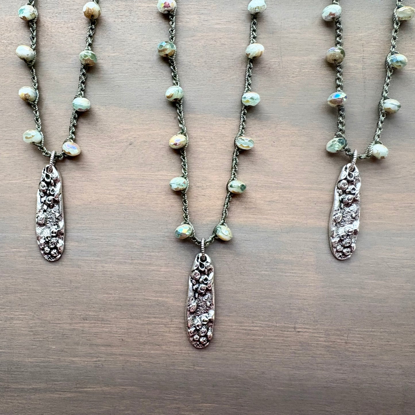 Three necklaces with pendant charms on a wooden surface