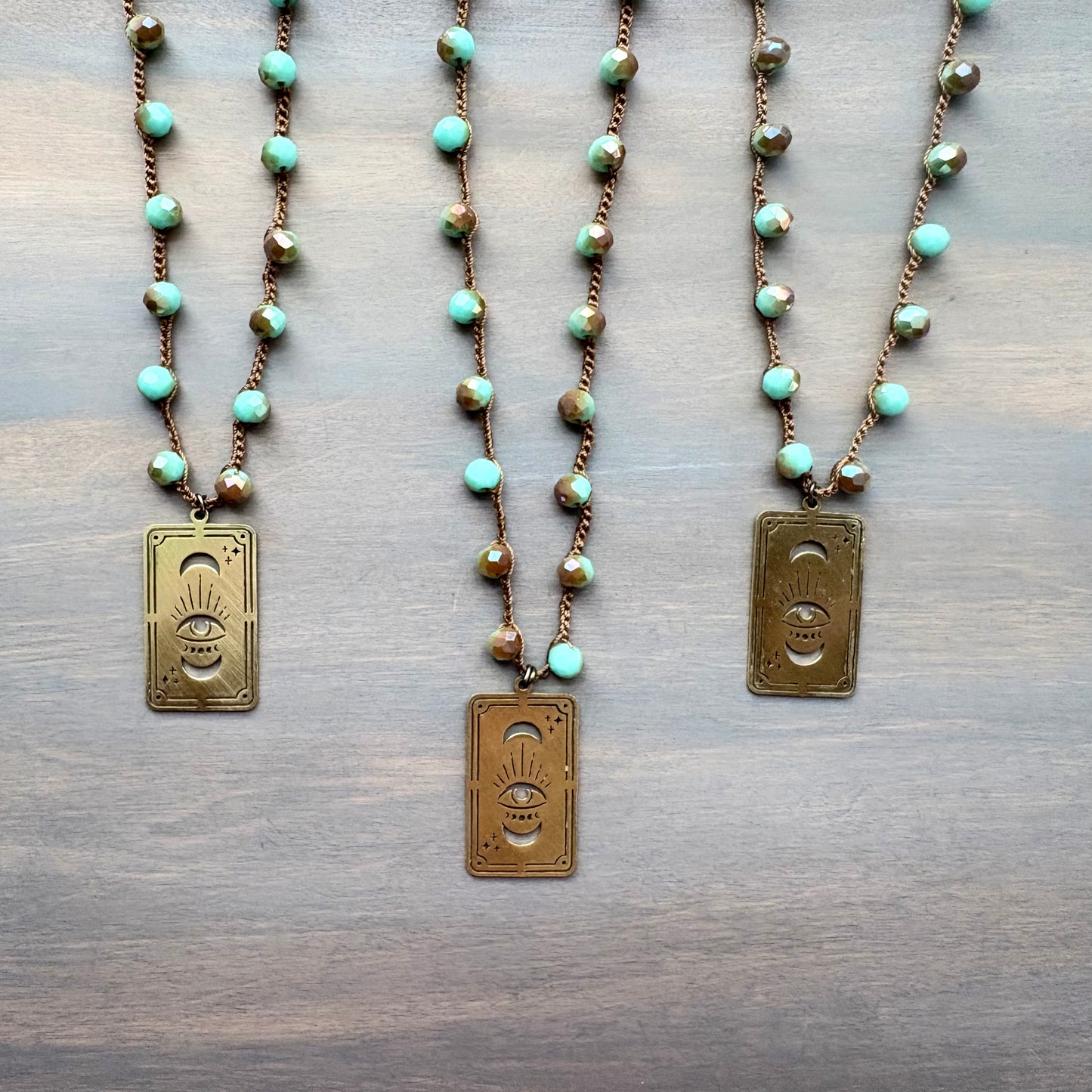 Three necklaces with turquoise beads and gold pendants on a wooden surface