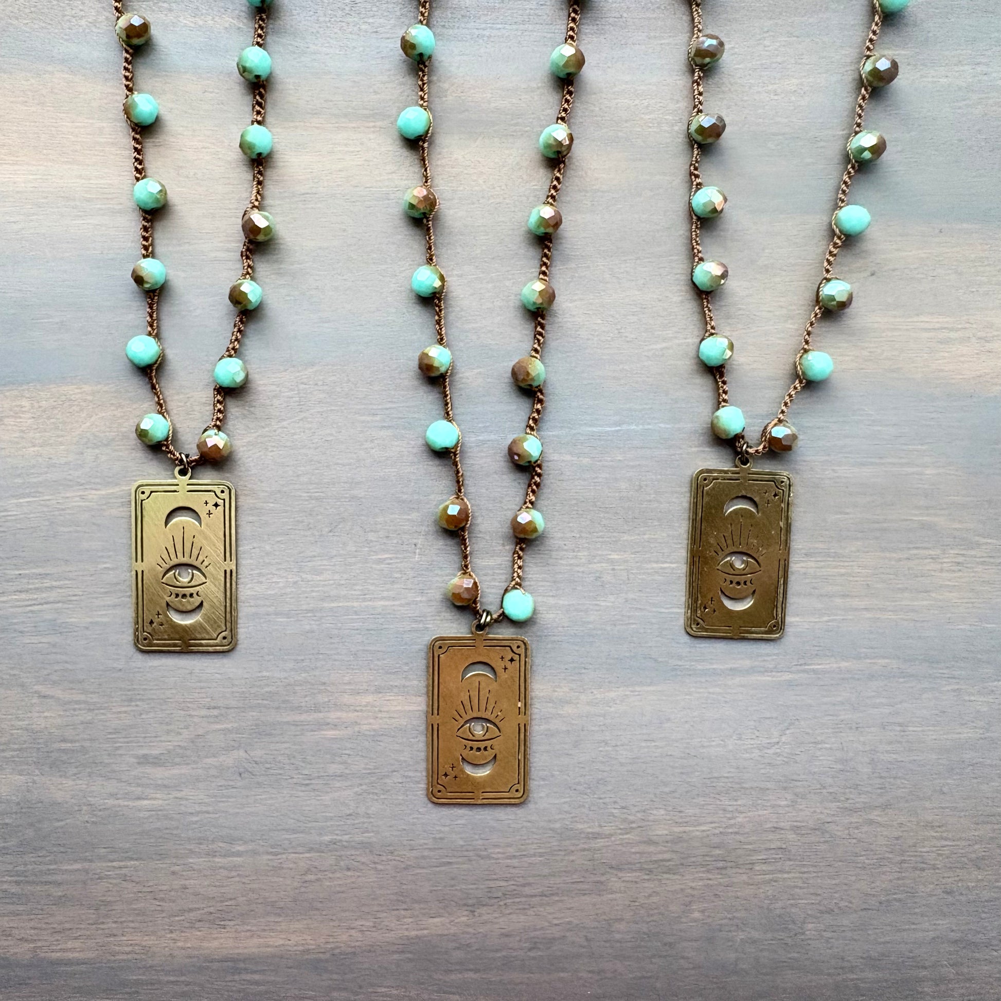 Three necklaces with turquoise beads and gold pendants on a wooden surface