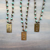 Three necklaces with turquoise beads and gold pendants on a wooden surface