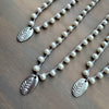 Two pearl necklaces with silver leaf pendants on a wooden surface