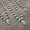 Three pearl necklaces with silver leaf pendants on a wooden surface