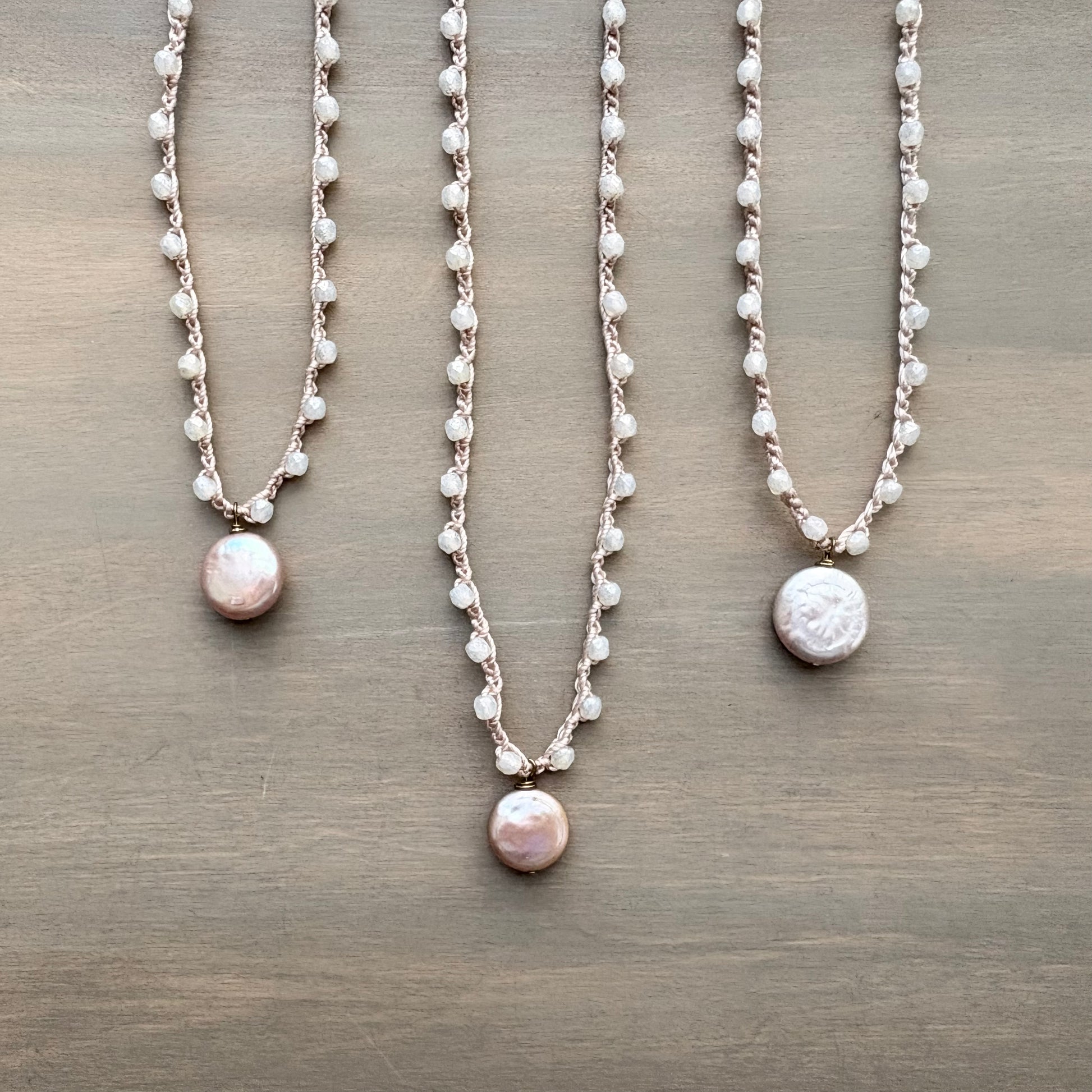 Three pearl necklaces on a wooden surface