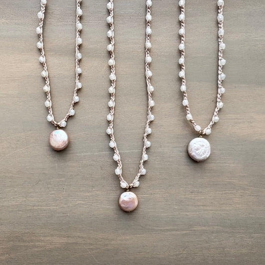 Three pearl necklaces on a wooden surface
