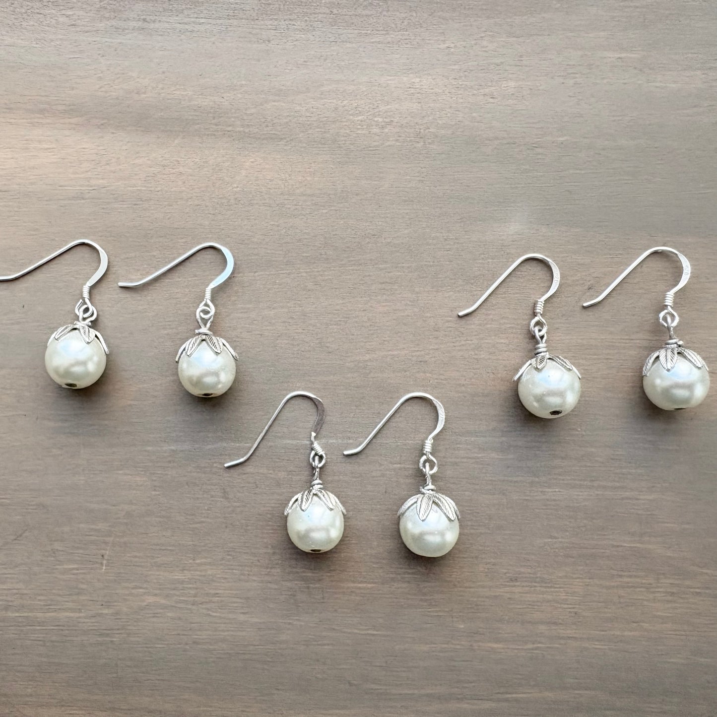 Set of pearl earrings on a wooden surface