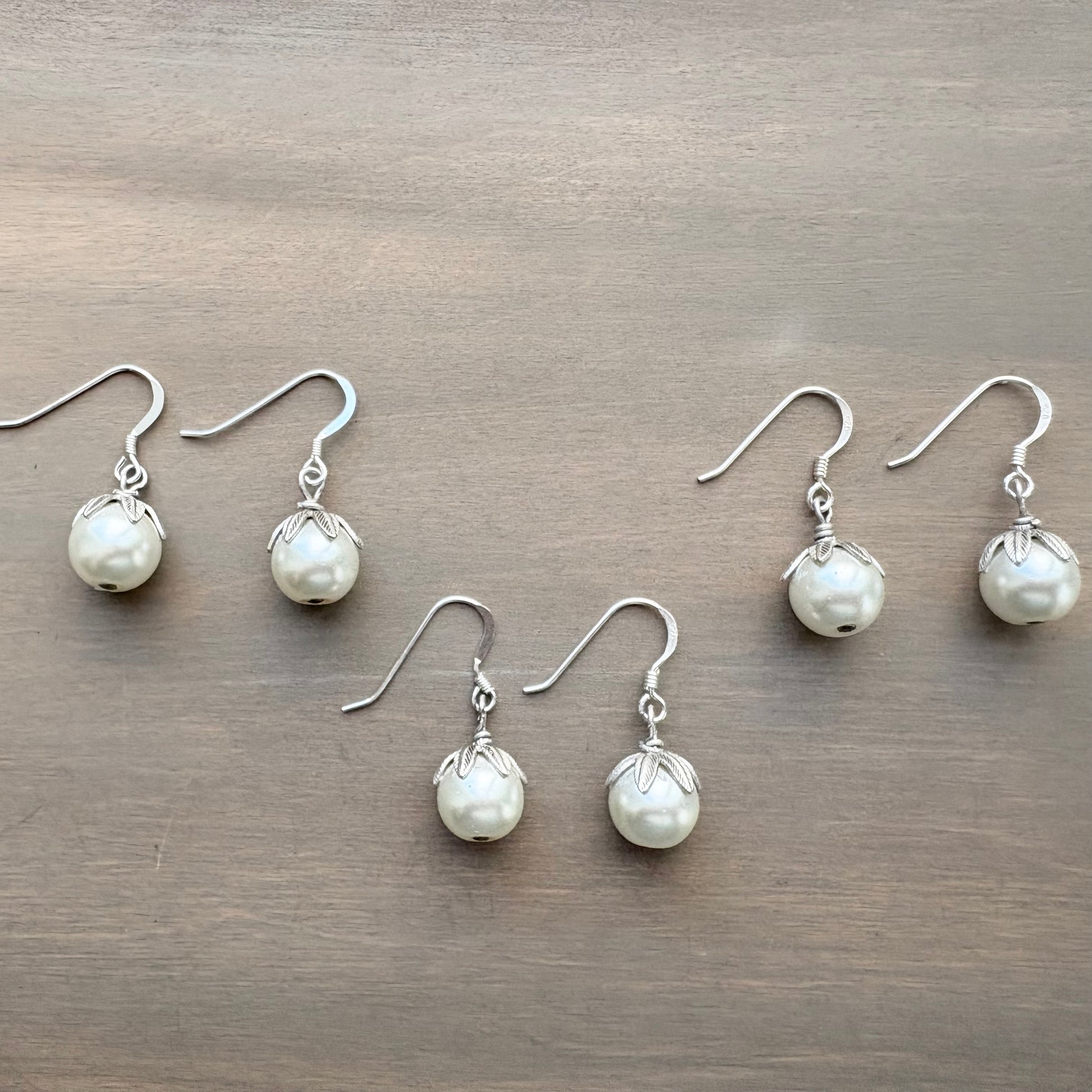 Set of pearl earrings on a wooden surface