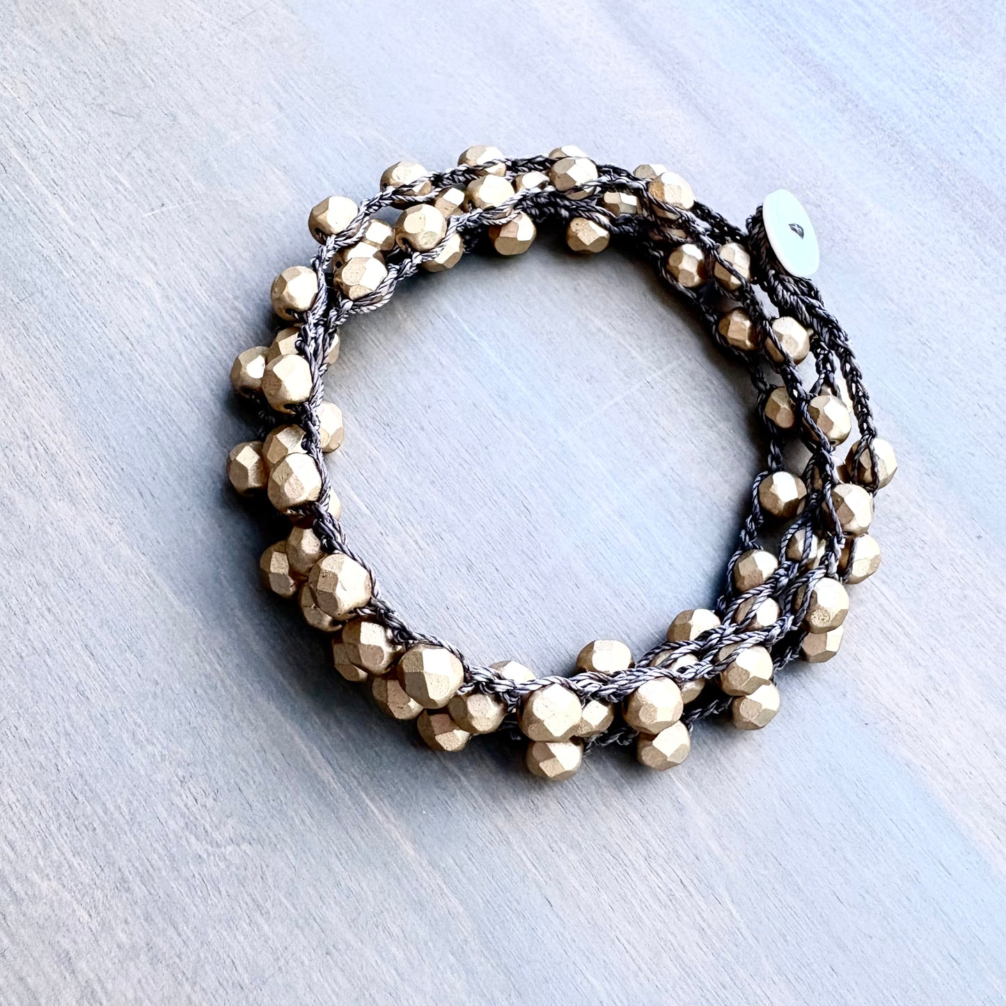 Bracelet with gold beads on a light gray background