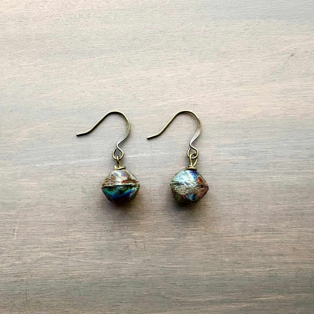 Pair of earrings with faceted gemstones on a wooden surface