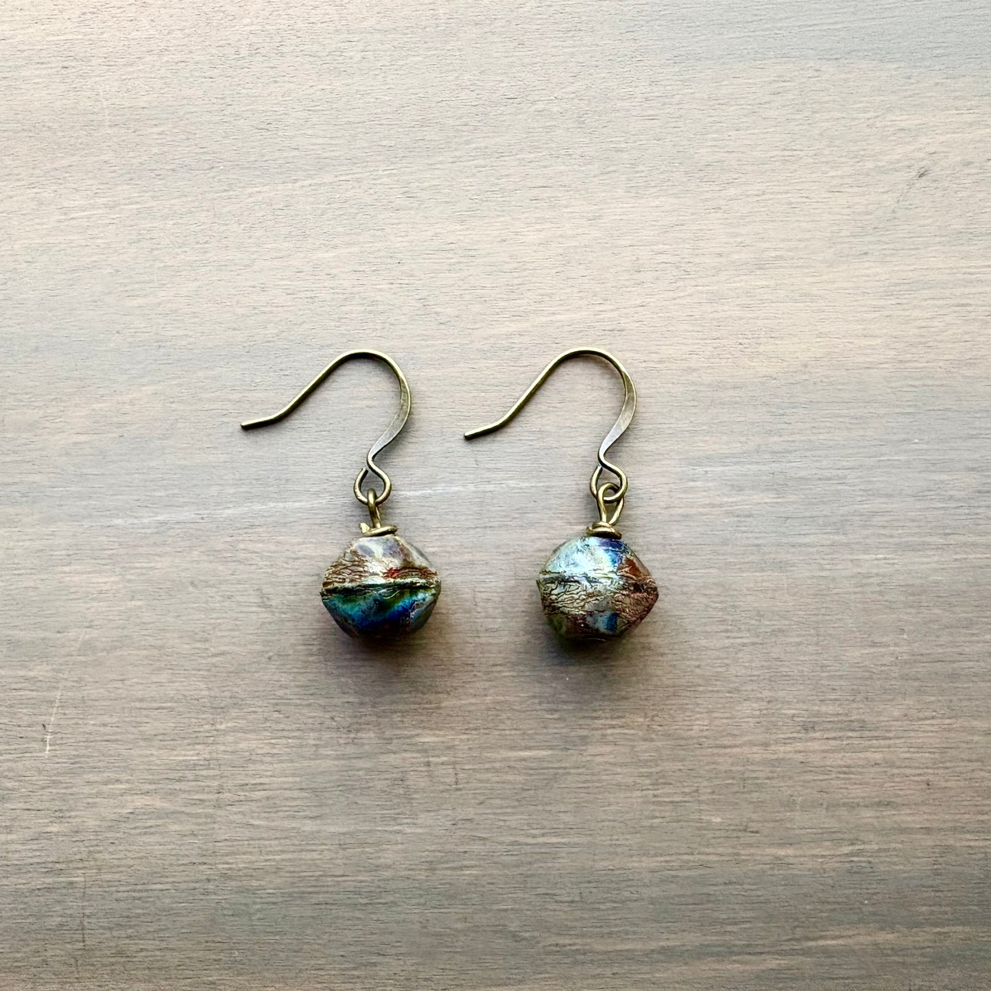 Pair of earrings with faceted gemstones on a wooden surface