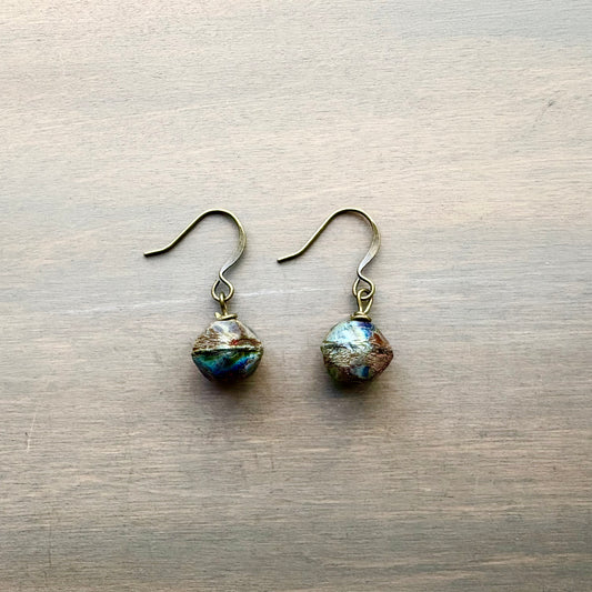 Pair of earrings with faceted gemstones on a wooden surface