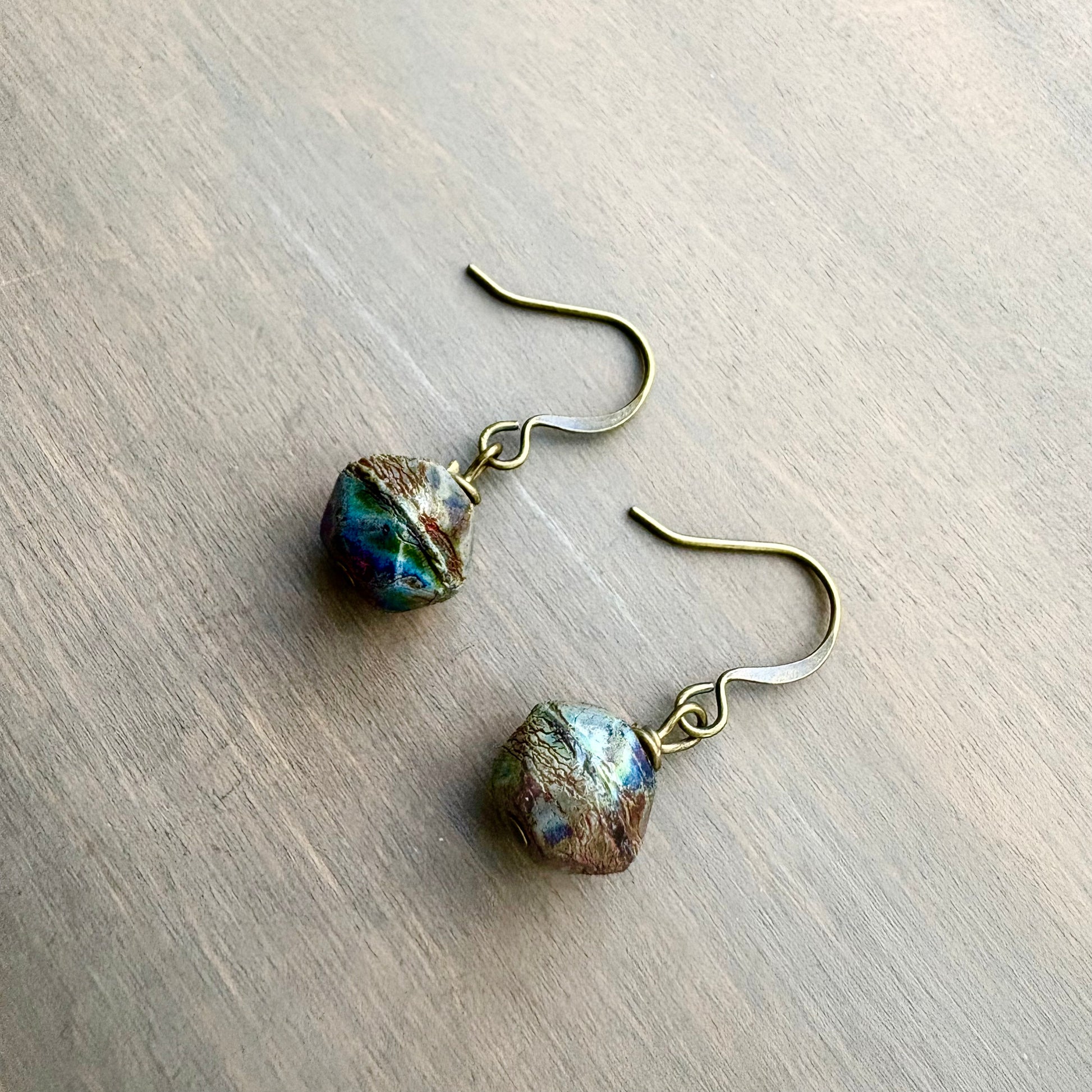 Pair of earrings with textured beads on a wooden surface