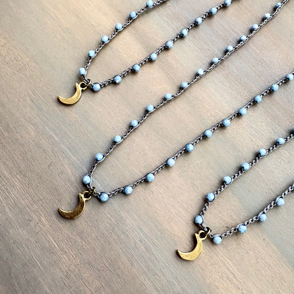 Necklace with gold crescent moon pendants on a wooden surface