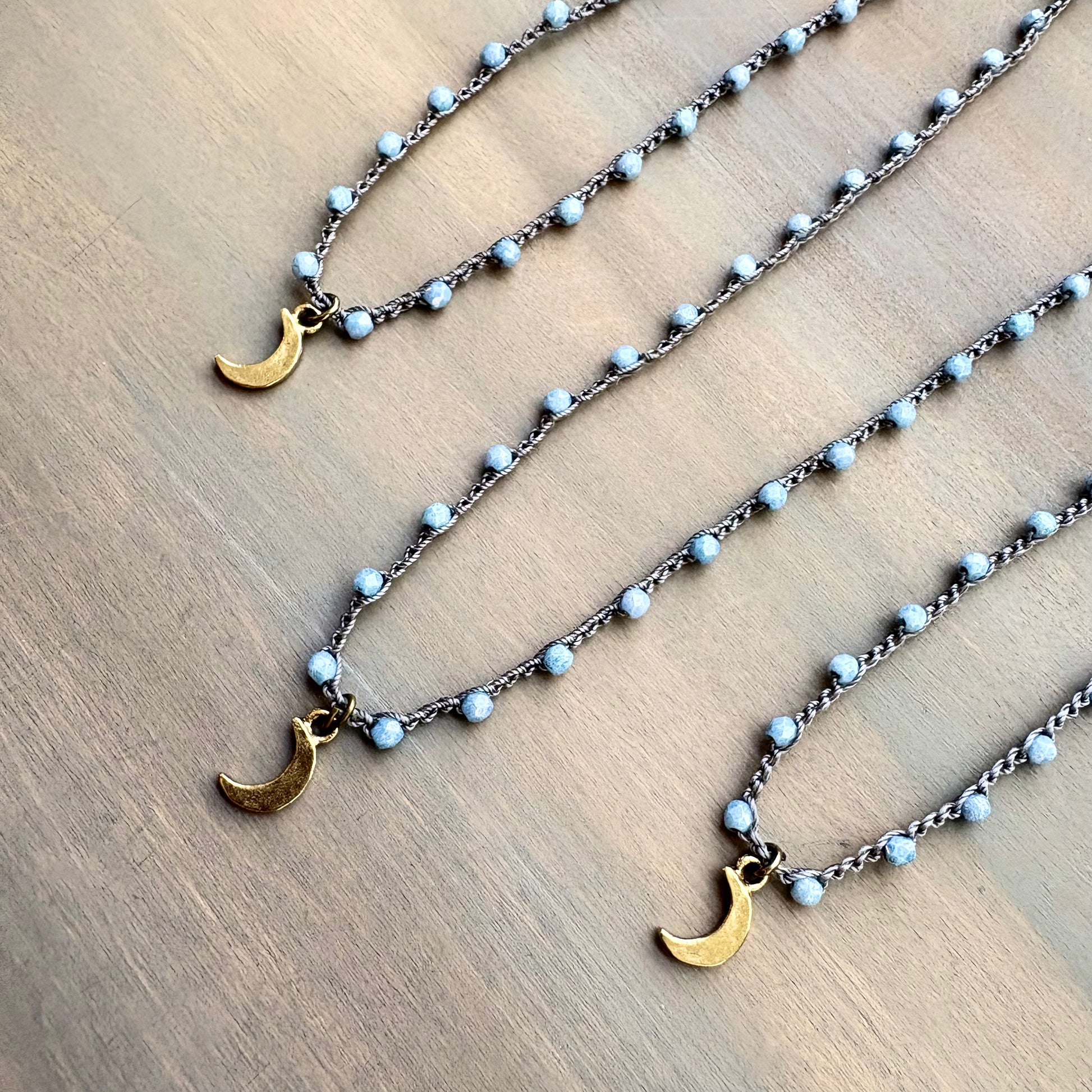 Necklace with gold crescent moon pendants on a wooden surface