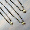 Two beaded necklaces with gold pendants on a light wooden surface