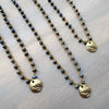 Two beaded necklaces with gold pendants on a textured surface