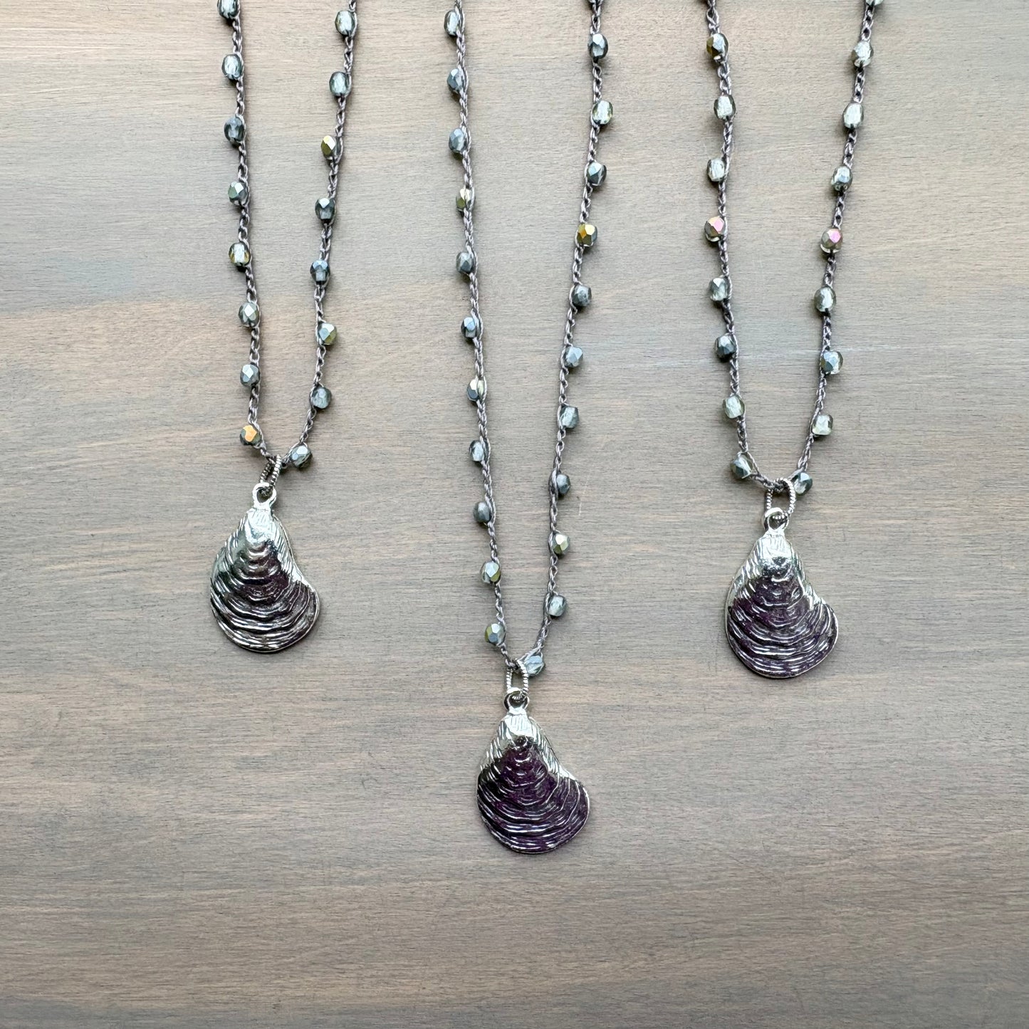 Three necklaces with shell pendants on a wooden surface