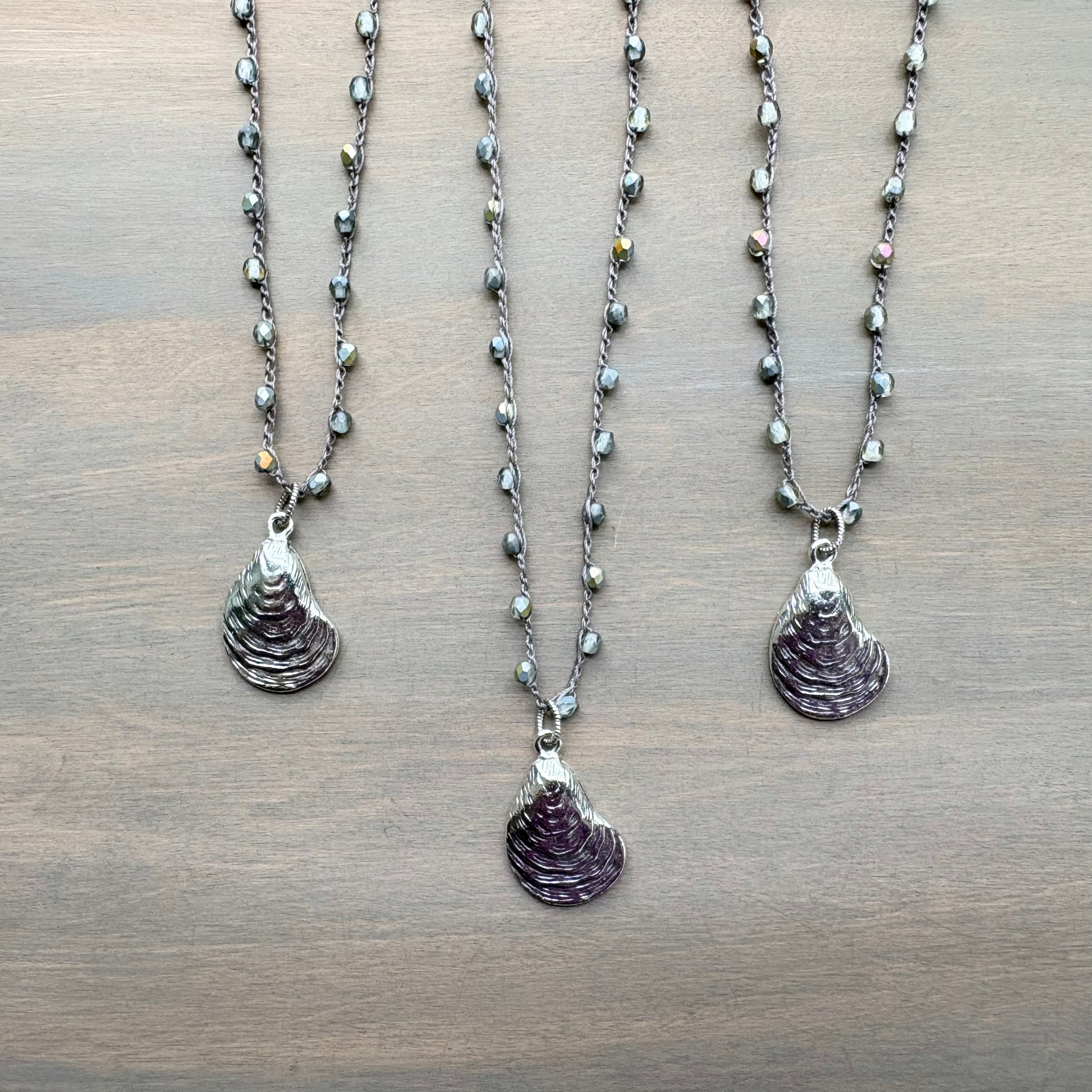 Three necklaces with shell pendants on a wooden surface
