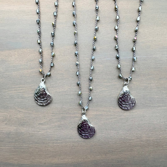 Three necklaces with shell pendants on a wooden surface