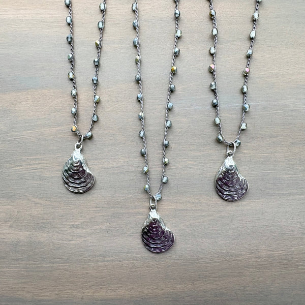 Three necklaces with shell pendants on a wooden surface
