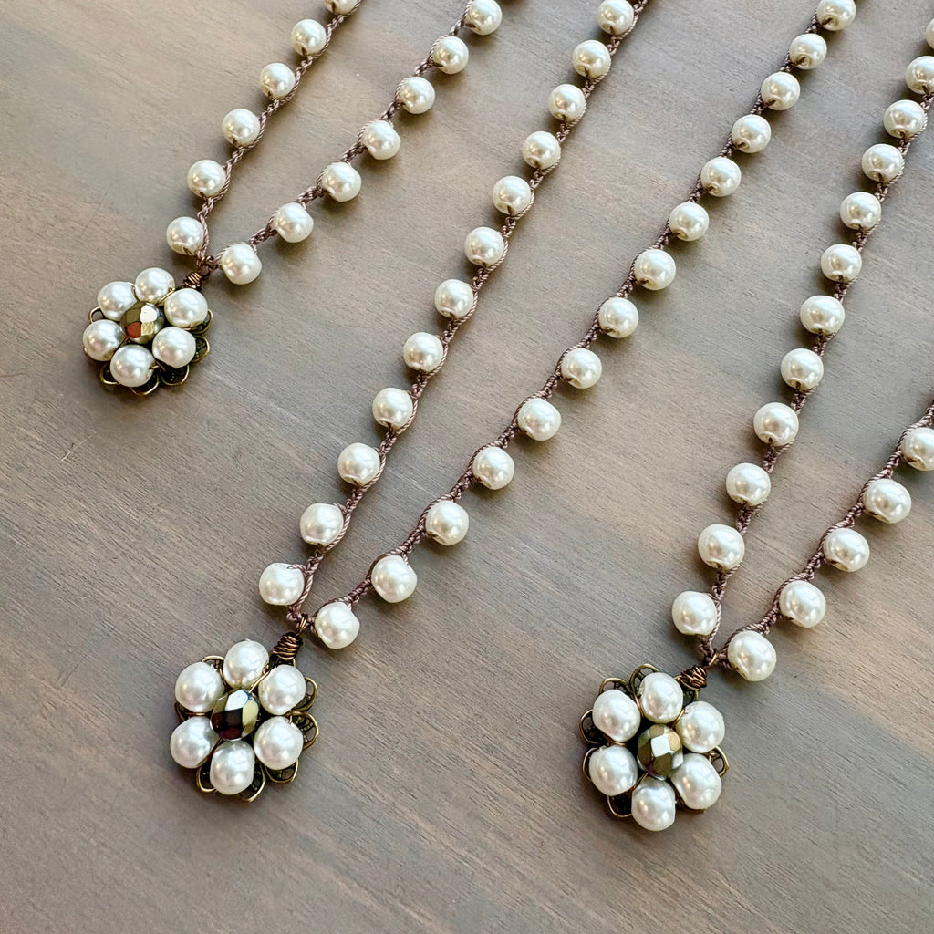 Pearl necklace with floral pendants on a wooden surface