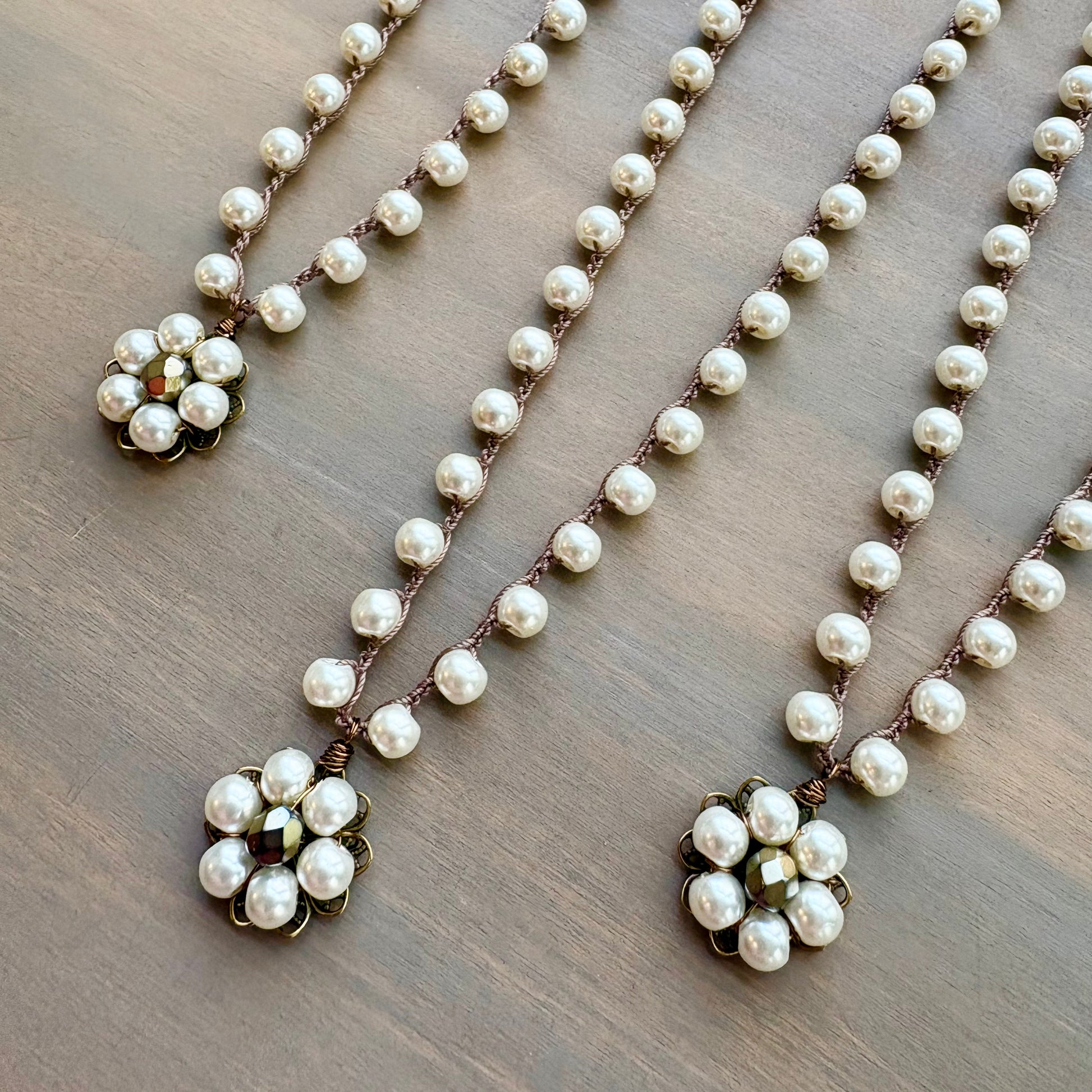 Pearl necklace with floral pendants on a wooden surface