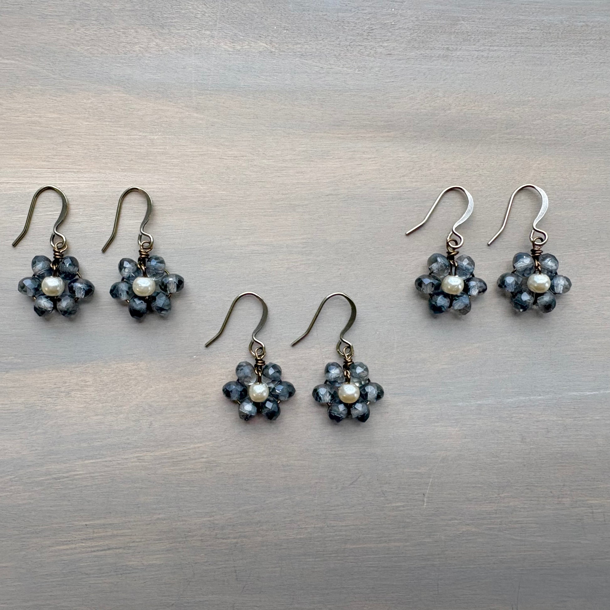 Pair of floral earrings with pearl-like stones on a metallic surface