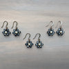 Pair of floral earrings with pearl-like stones on a metallic surface