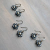 Set of flower-shaped earrings with blue and pearl beads on a wooden surface