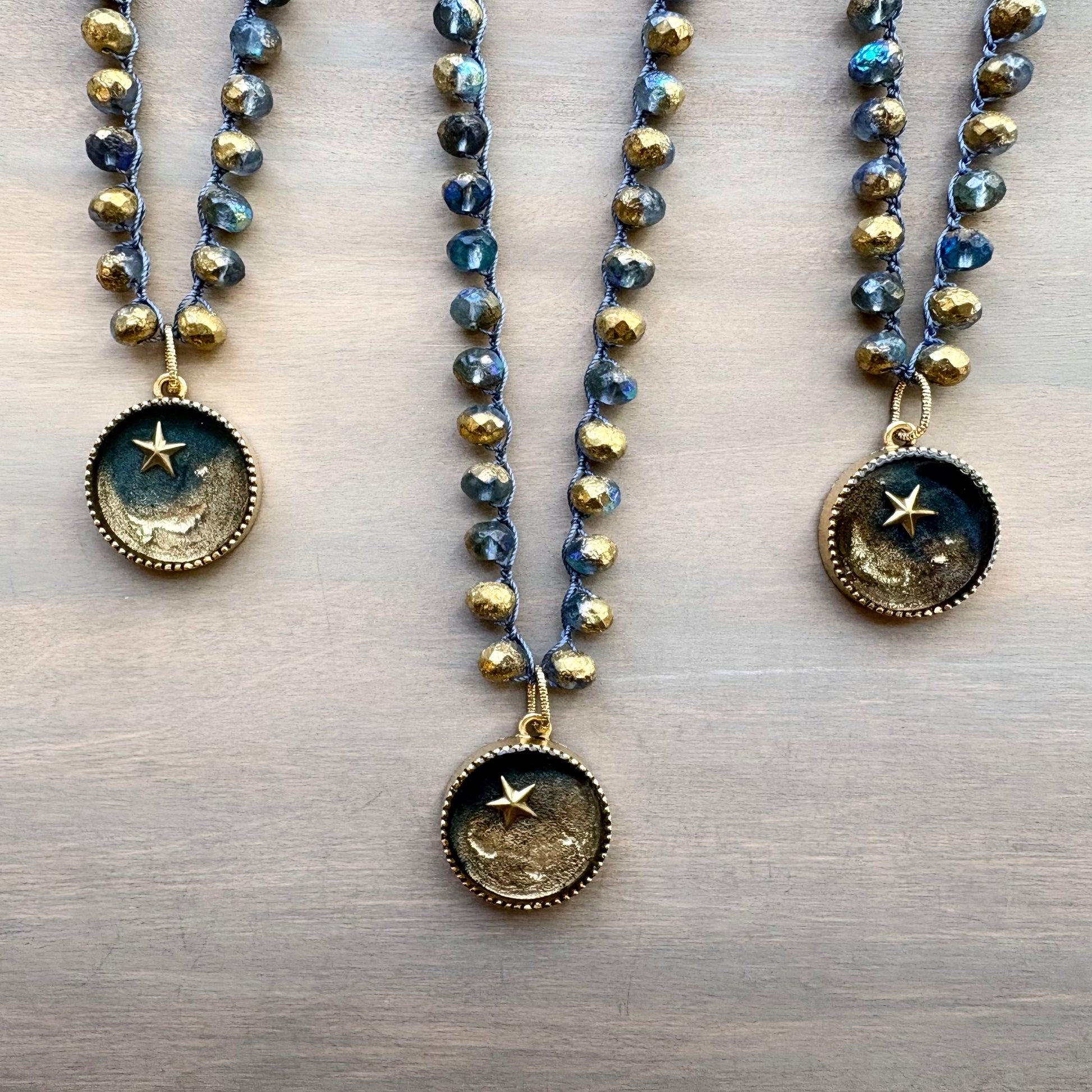 Two beaded necklaces with star-themed pendants on a wooden surface